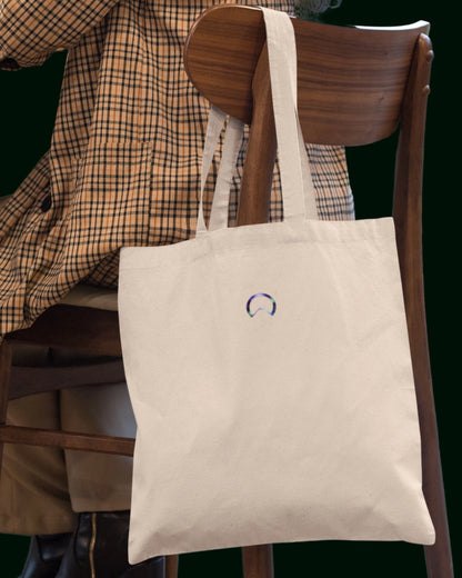 Ein nachhaltiger Jutebeutel aus recycelter Baumwolle und recycelter Polyester in Naturfarbe (besch) - verziert mit der Blume des Lebens auf der einen und dem Alpha-i-Omega auf der anderen Seite. Perfekt für Freizeit, Arbeit, Universität und Festivals – stilvoll und umweltfreundlich